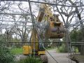 Construction excavator crushing wire fence