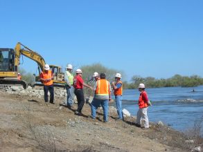 Construction workers overseeing work along river